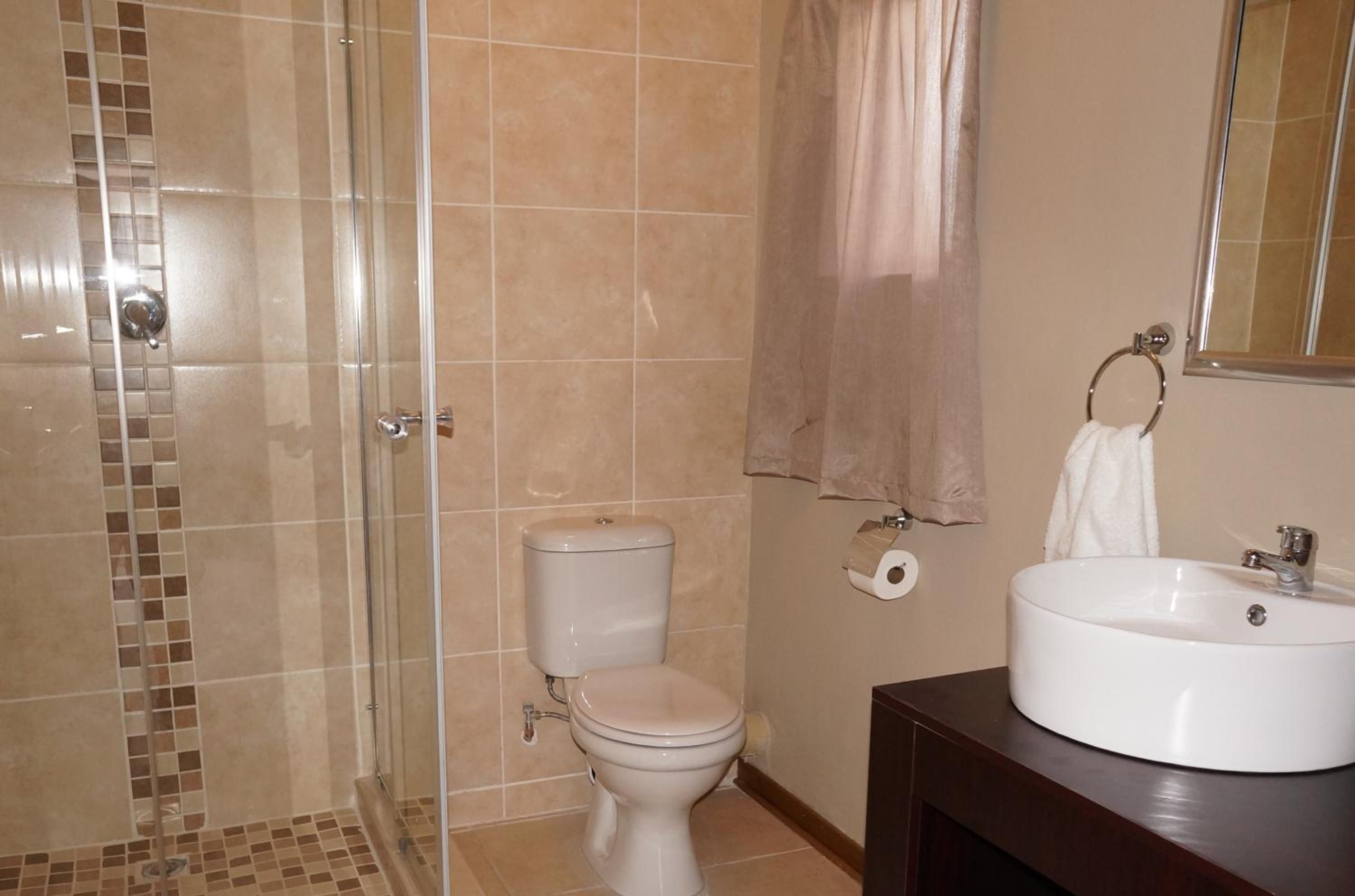 Un baño con ducha de vidrio, inodoro y lavabo con espejo.