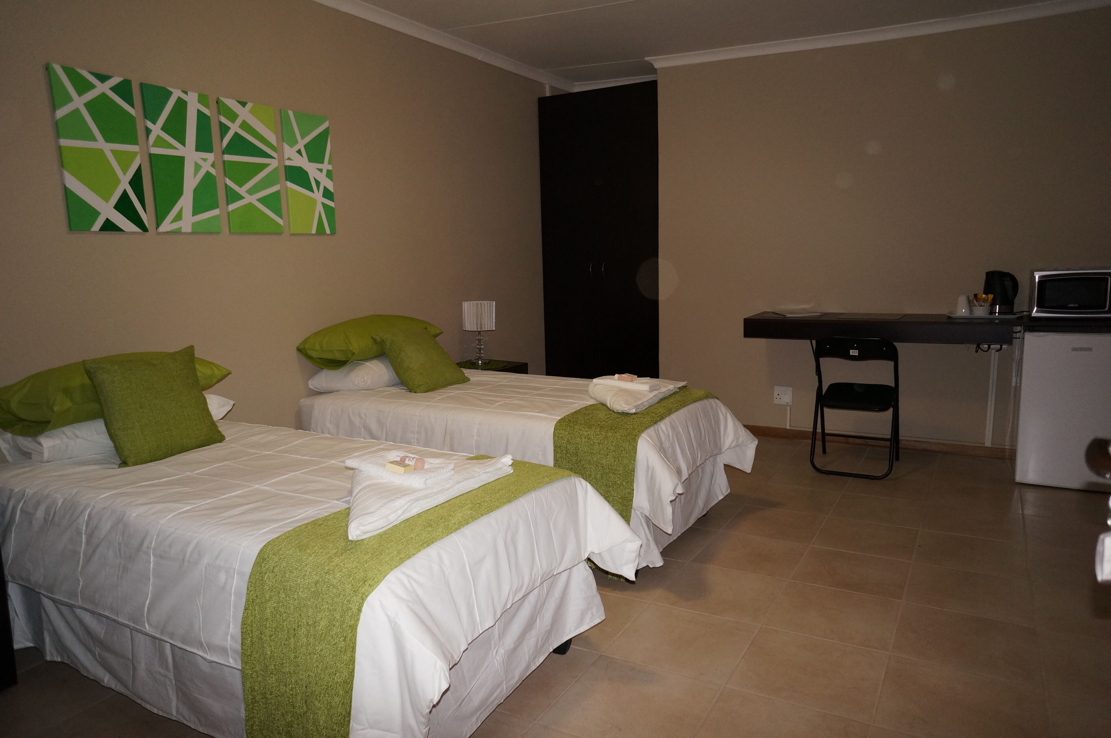 A hotel room with two beds, a desk, a chair, a microwave, and a coffee maker.