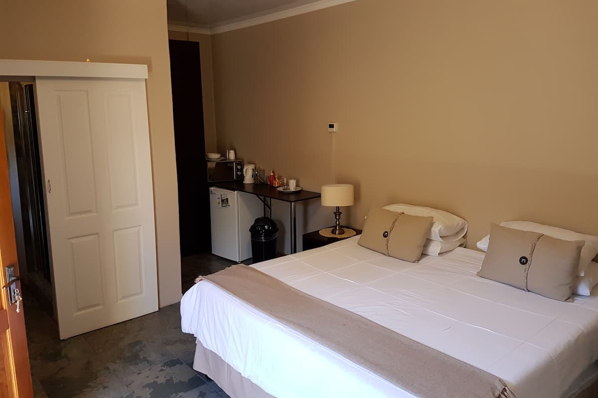 Ein Hotelzimmer mit Bett, Nachttisch, Lampe und einer kleinen Küchenzeile.