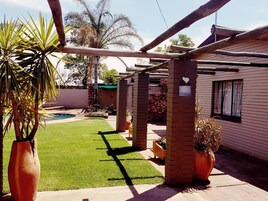 Um quintal com piscina, pergolado e uma casa de tijolos.