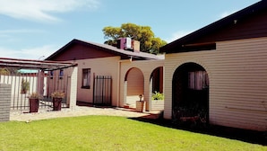 A two-story building with a flat roof, a covered patio area, and a well-maintained lawn.