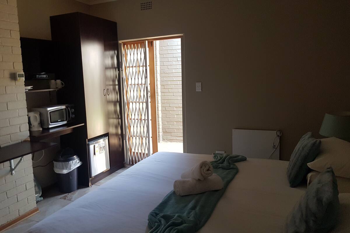 Ein Schlafzimmer mit einem Bett, einer Mikrowelle, einem Mülleimer und einem Fenster mit Blick nach draußen.