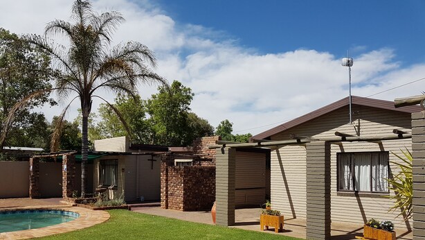 A residential property with a swimming pool, a covered patio, and a brick house.