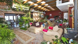 Un patio interior con mobiliario de mimbre, plantas en macetas y una pared de ladrillo.