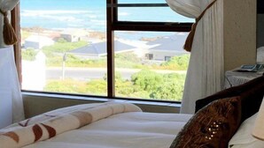 Un dormitorio con cama, cortinas y vistas al océano.
