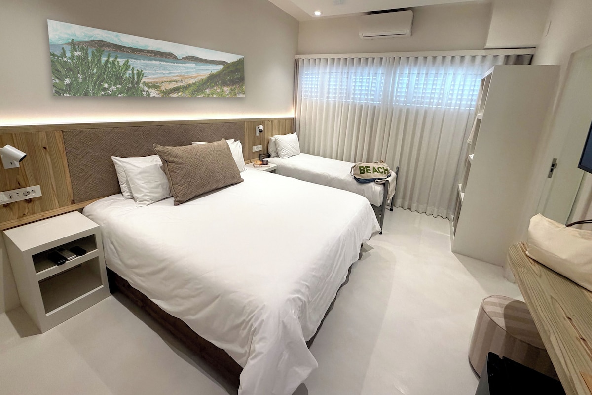 Una habitación de hotel con una cama grande, una mesita de noche, un televisor y un cuadro en la pared.