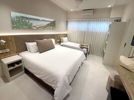 Una habitación de hotel con una cama grande, una mesita de noche, un televisor y un cuadro en la pared.