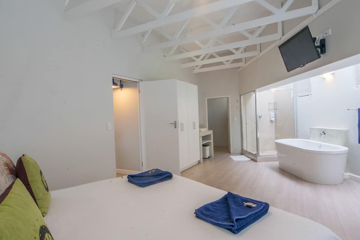 Quarto com cama grande, banheira e televisão na parede.