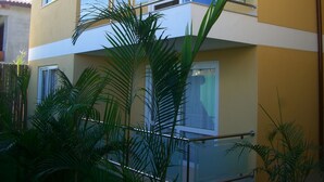 Un immeuble à deux étages doté de balcons, de grandes fenêtres et entouré de verdure.