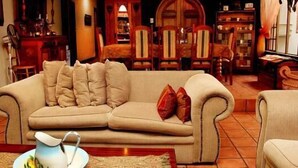 Un salon avec un canapé beige, une table basse et un coin repas comprenant des chaises et une table en bois.