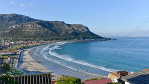 A coastal town with a beach, houses, and a mountain in the background. - A Whale of a Time (Cape Town)