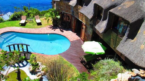 A house with a large swimming pool, a deck, and a view of the ocean. - A Whale of a Time (Cape Town)