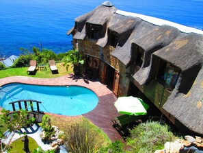 A house with a large swimming pool, a deck, and a view of the ocean. - A Whale of a Time (Cape Town)