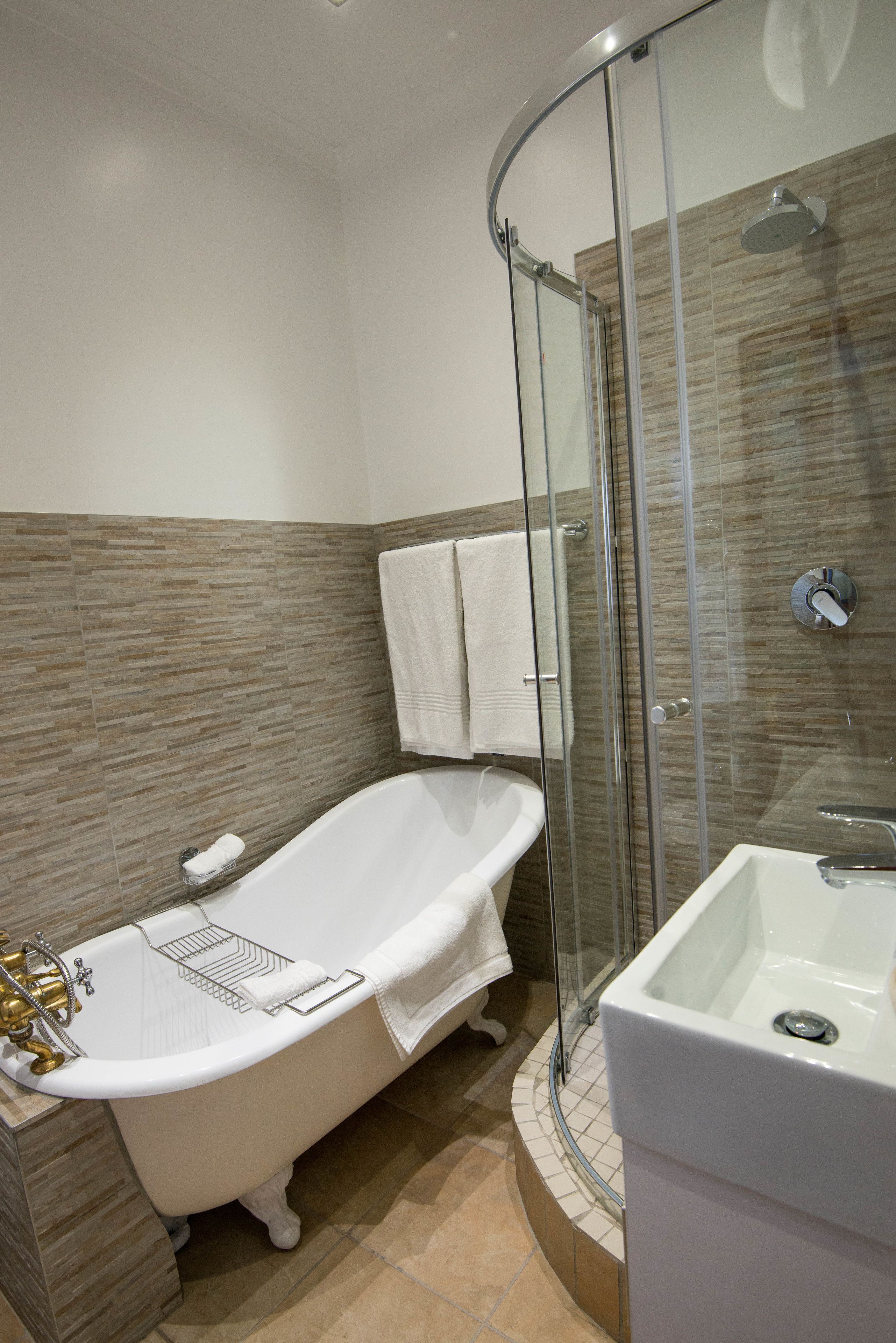 A bathroom with a freestanding bathtub, a glass-enclosed shower, and a separate sink area.