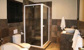 A bathroom with a glass-enclosed shower, a toilet, a sink, and a towel rack.