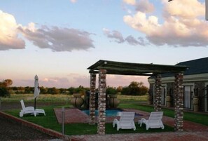 A covered outdoor area with lounge chairs and a pool. - Almar Exclusive Game Ranch (Bloemhof)
