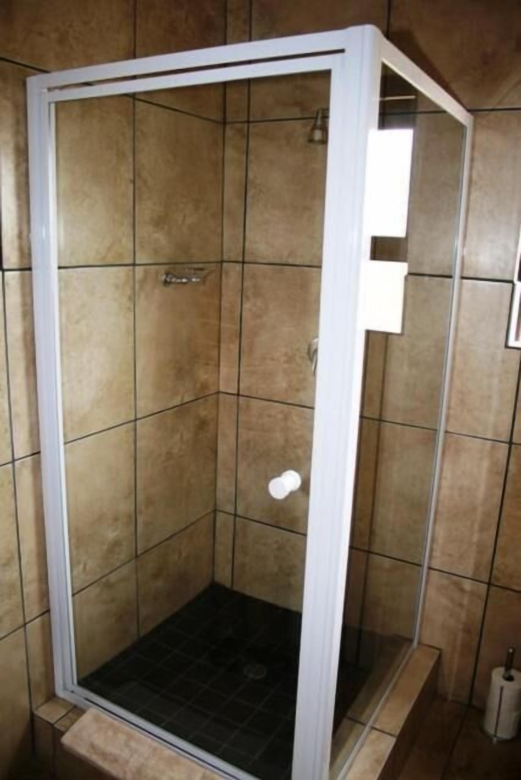Un espace de douche avec un cadre blanc, des murs carrelés et un sol noir.