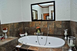 A modern bathroom with a freestanding bathtub, a large mirror, and a small sink.