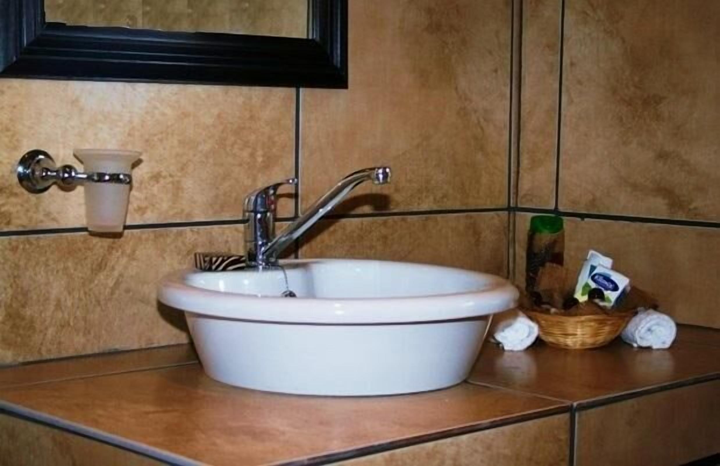 Ein Badezimmer mit einem weißen Waschbecken, einem Spiegel darüber und einem Handtuchhalter links.