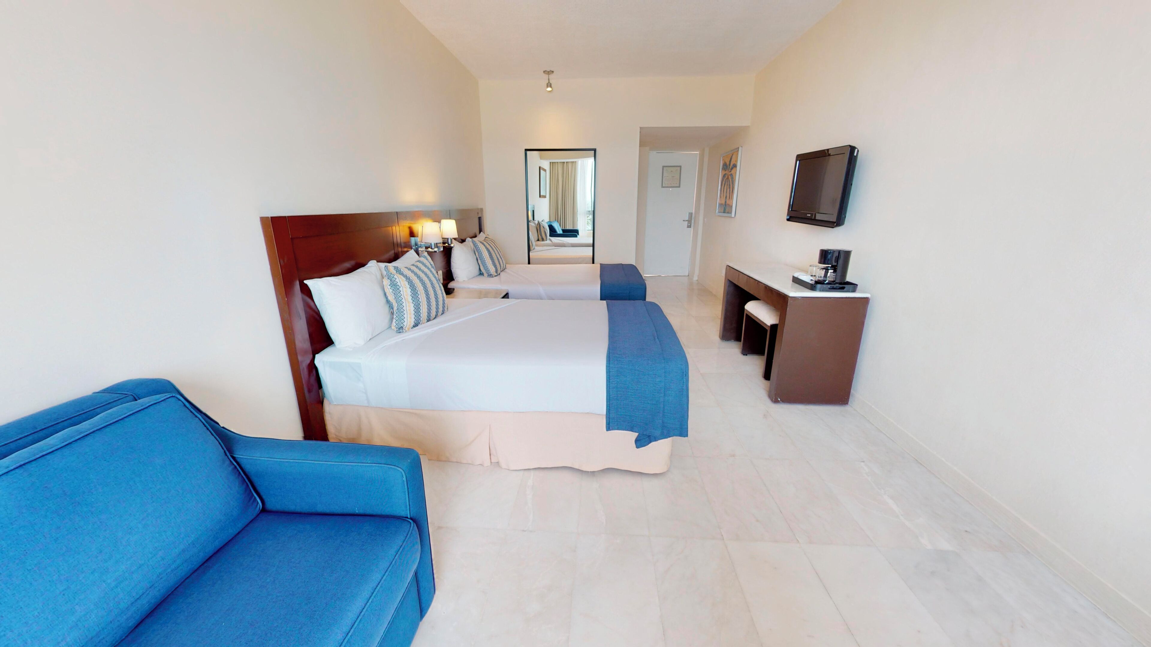 A hotel room with a bed, a desk, a chair, and a television.