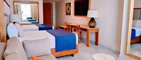 A hotel room with two beds, a desk, a chair, a lamp, and a mirror.