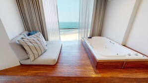 A modern room with a wooden floor, a sofa with striped pillows, and a large bathtub. - Park Royal Mazatlan managed by Accor (Mazatlán)