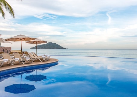 Alberca al aire libre, sombrillas en la alberca y camastros . Park Royal Mazatlan managed by Accor