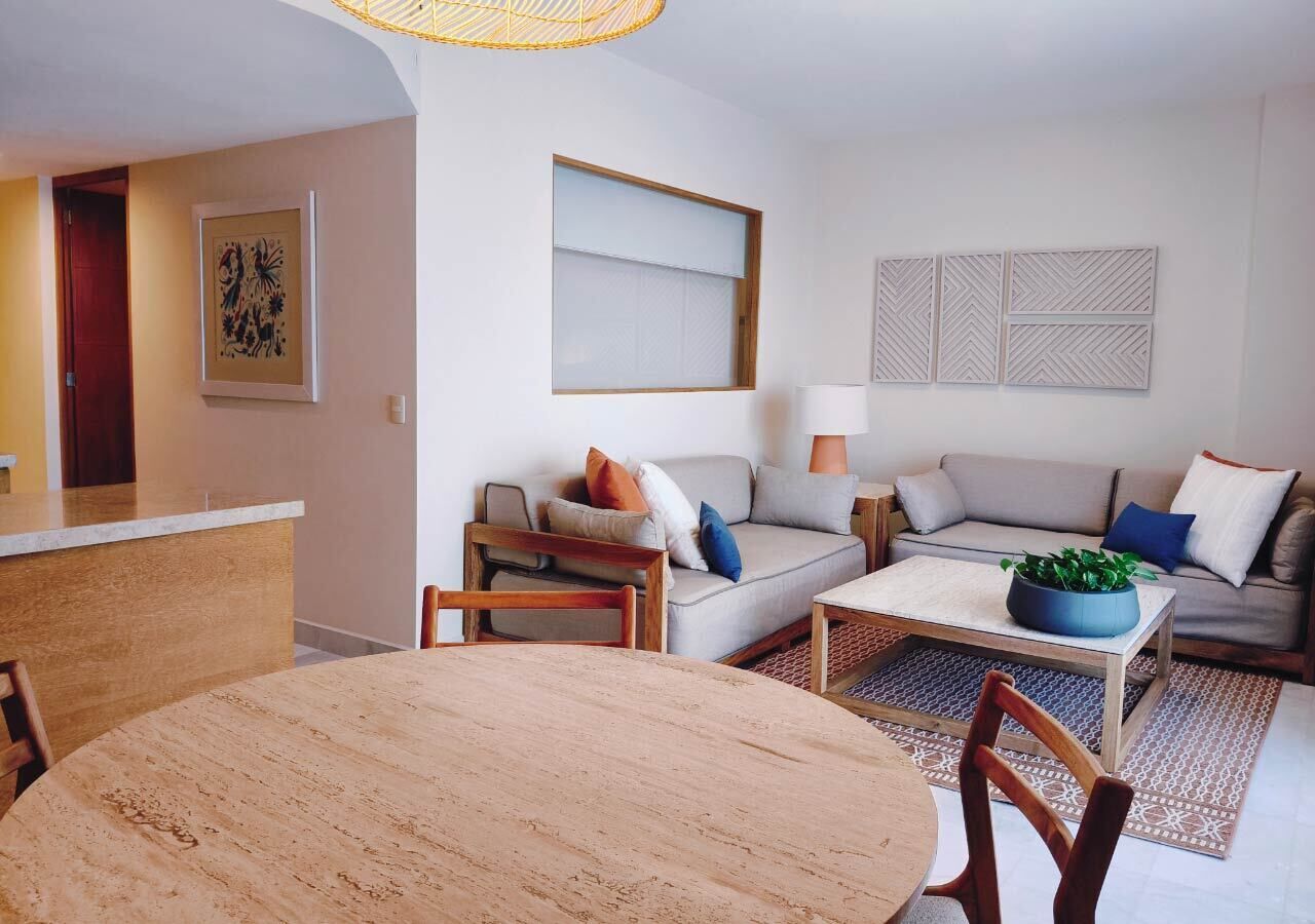 A modern living room with a sofa, coffee table, and dining table.