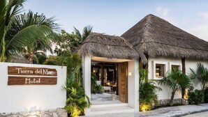 A hotel entrance with a thatched roof, a signboard, and a pathway leading to the main building. - Tierra del Mar Hotel - Adult Only (Isla Holbox)