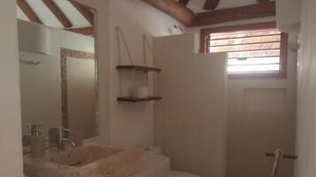 Une salle de bain avec un plafond en bois, un lavabo, des toilettes et un espace douche.