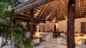 A cozy, open-plan living area with a thatched roof, comfortable seating, and a dining area. - Tierra del Mar Hotel - Adult Only (Isla Holbox)