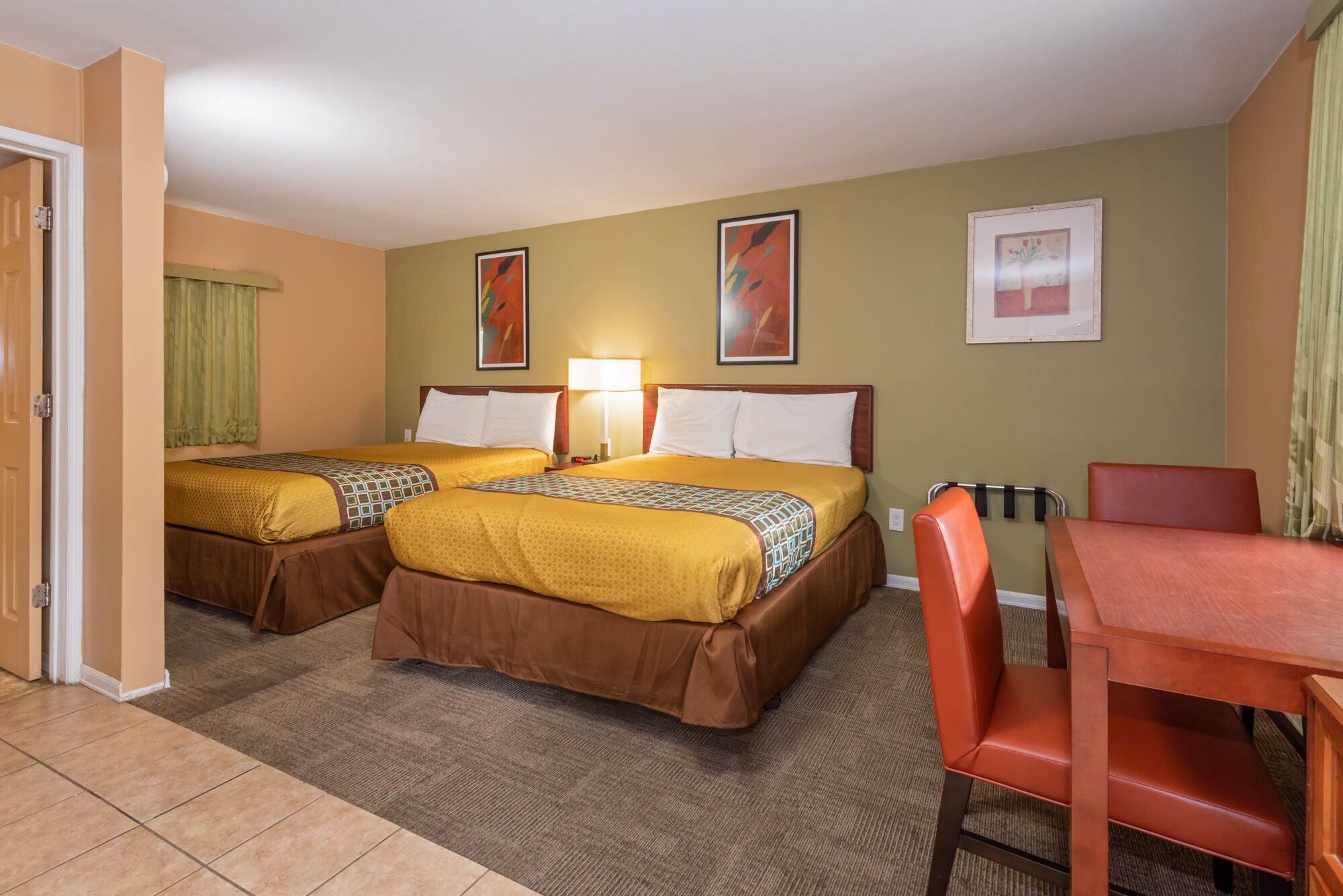A hotel room with two beds, a table, and chairs.