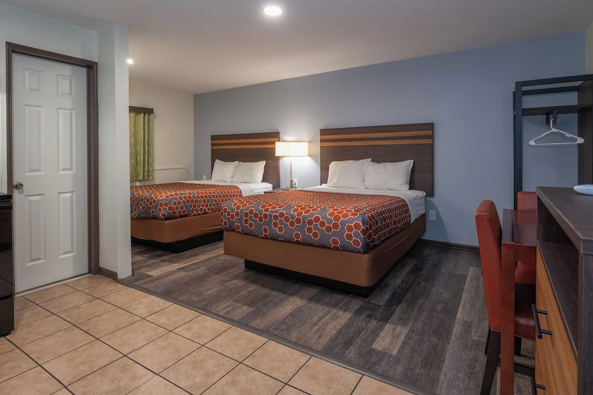 A hotel room with two beds, a desk, and a chair.