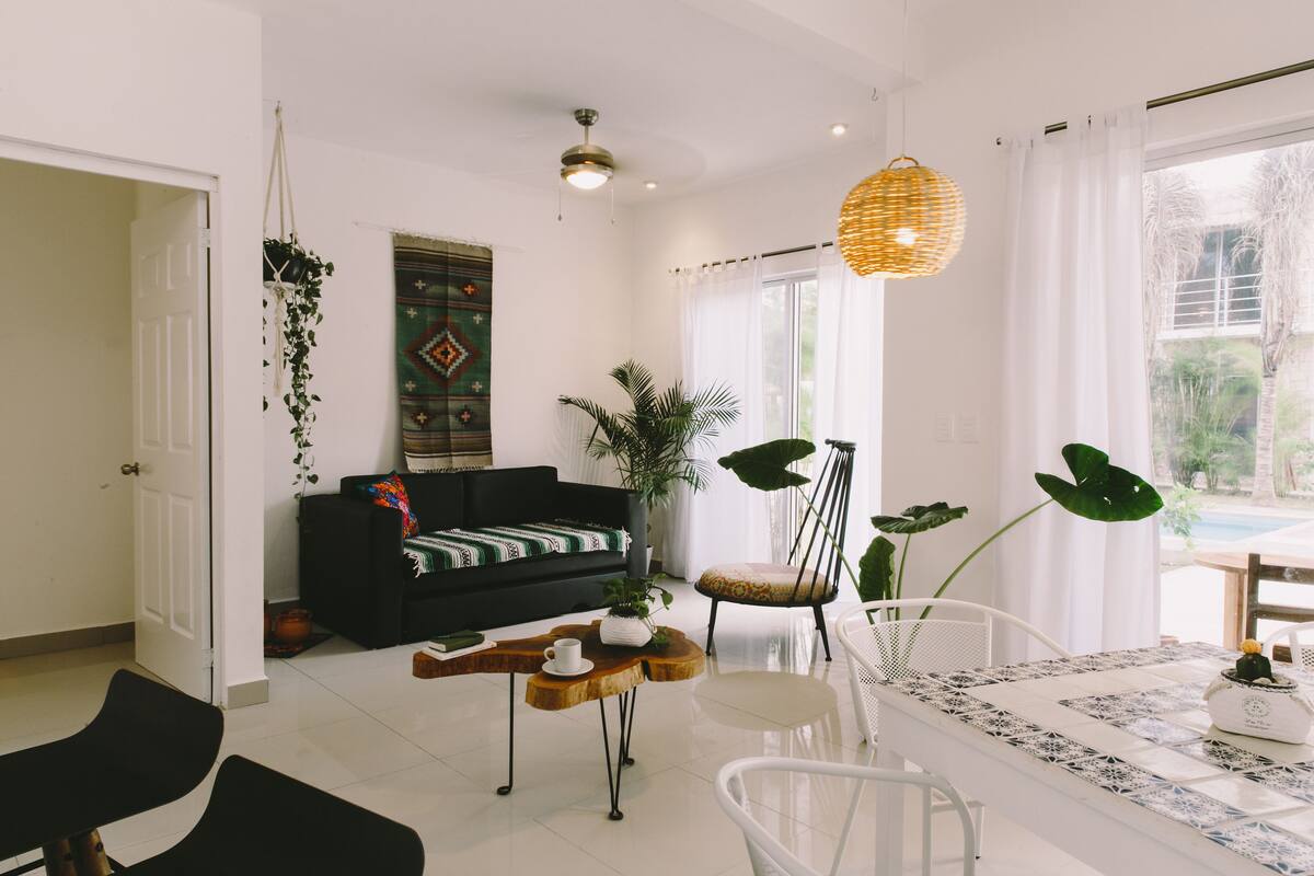 Ein modernes Wohnzimmer mit einem schwarzen Sofa, einem Couchtisch und einem Essbereich mit Tisch und Stühlen.