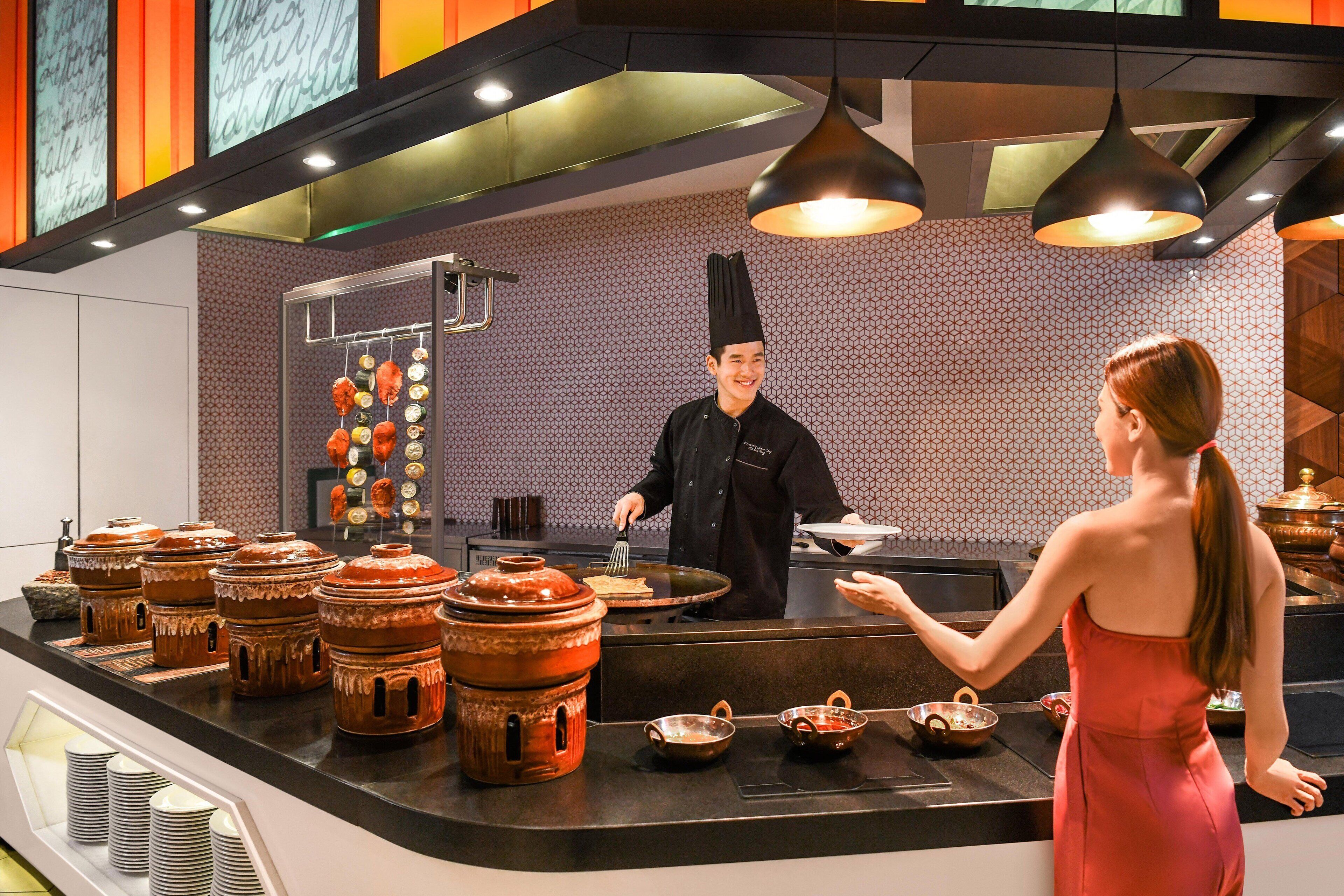 Una cocina moderna con un chef y un camarero, que incluye un mostrador con utensilios de cocina tradicionales y un salpicadero con diseño.