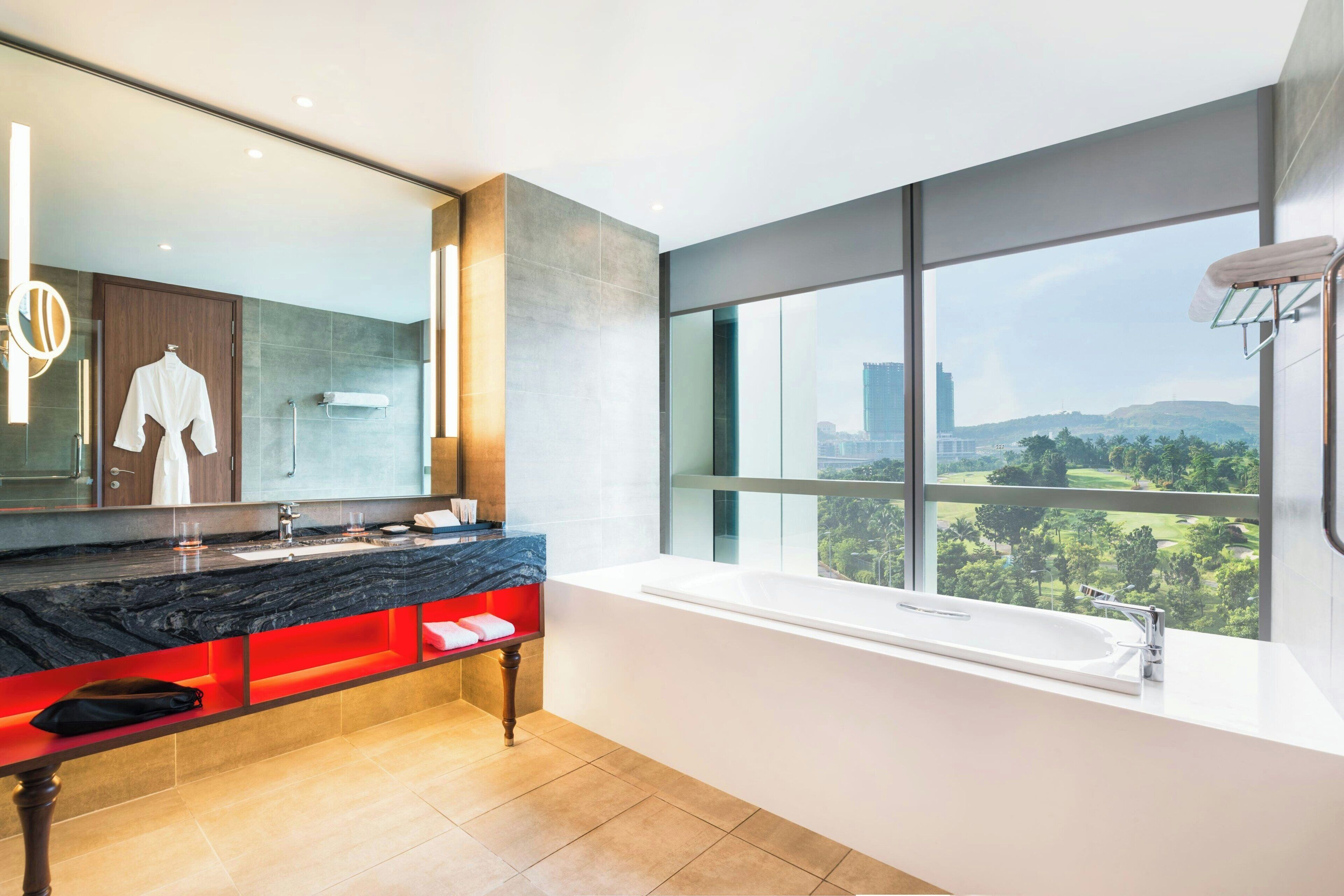 A modern bathroom with a large window, a bathtub, and a vanity with a mirror.