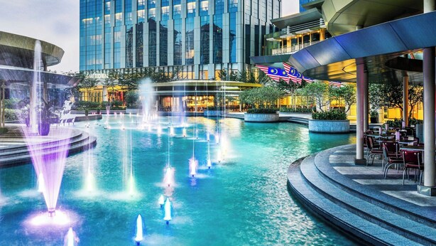 Un hotel moderno con un llamativo letrero Meridian, una amplia piscina exterior con fuentes y un edificio contemporáneo con un diseño de techo singular.