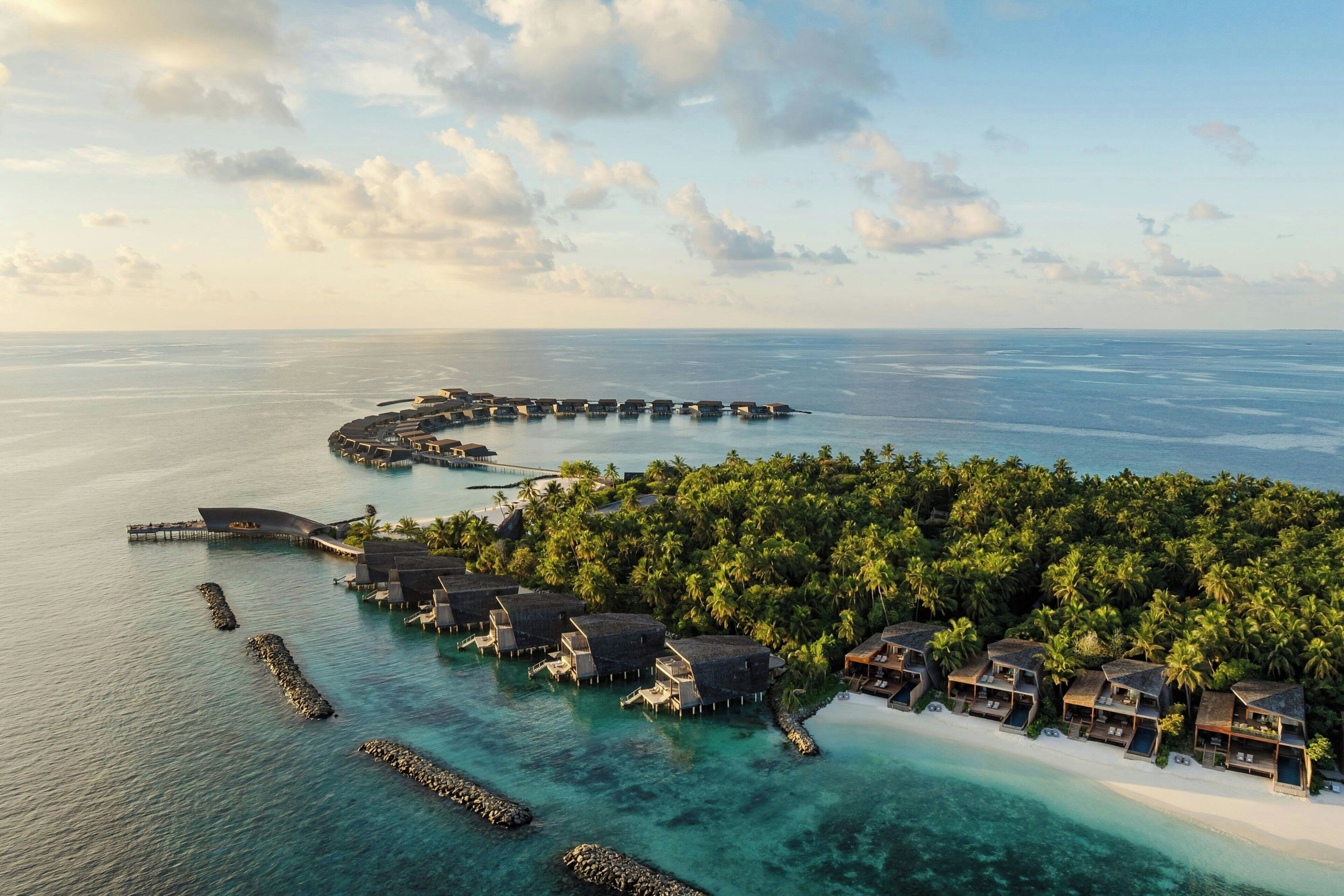 Un resort sobre el agua con alojamientos tipo bungalow, un muelle y una playa.