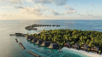 Un resort sobre el agua con alojamientos tipo bungalow, un muelle y una playa.