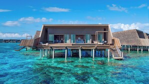 A modern overwater bungalow with a large balcony, clear blue water, and a wooden deck. - The St. Regis Maldives Vommuli Resort (Vommuli)