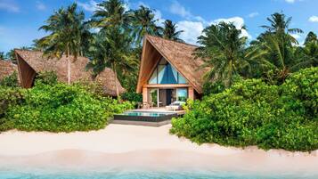 Un resort con bungalow sull'acqua, una piscina e vegetazione rigogliosa.