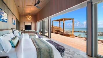 Relax in this serene beachfront room with a large bed, ceiling fan, and ocean views.