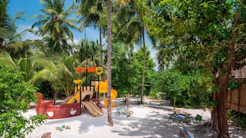 Un parque infantil en la playa con toboganes y una estructura de juego con forma de barco.