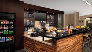 A modern café with a wooden counter, a beverage dispenser, and a menu board.