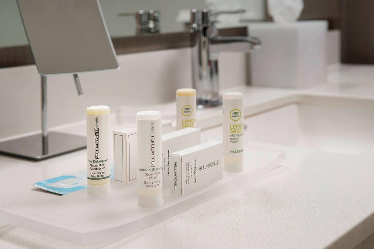 A bathroom counter with various personal care products, including a tube of balm and a bottle of shampoo.