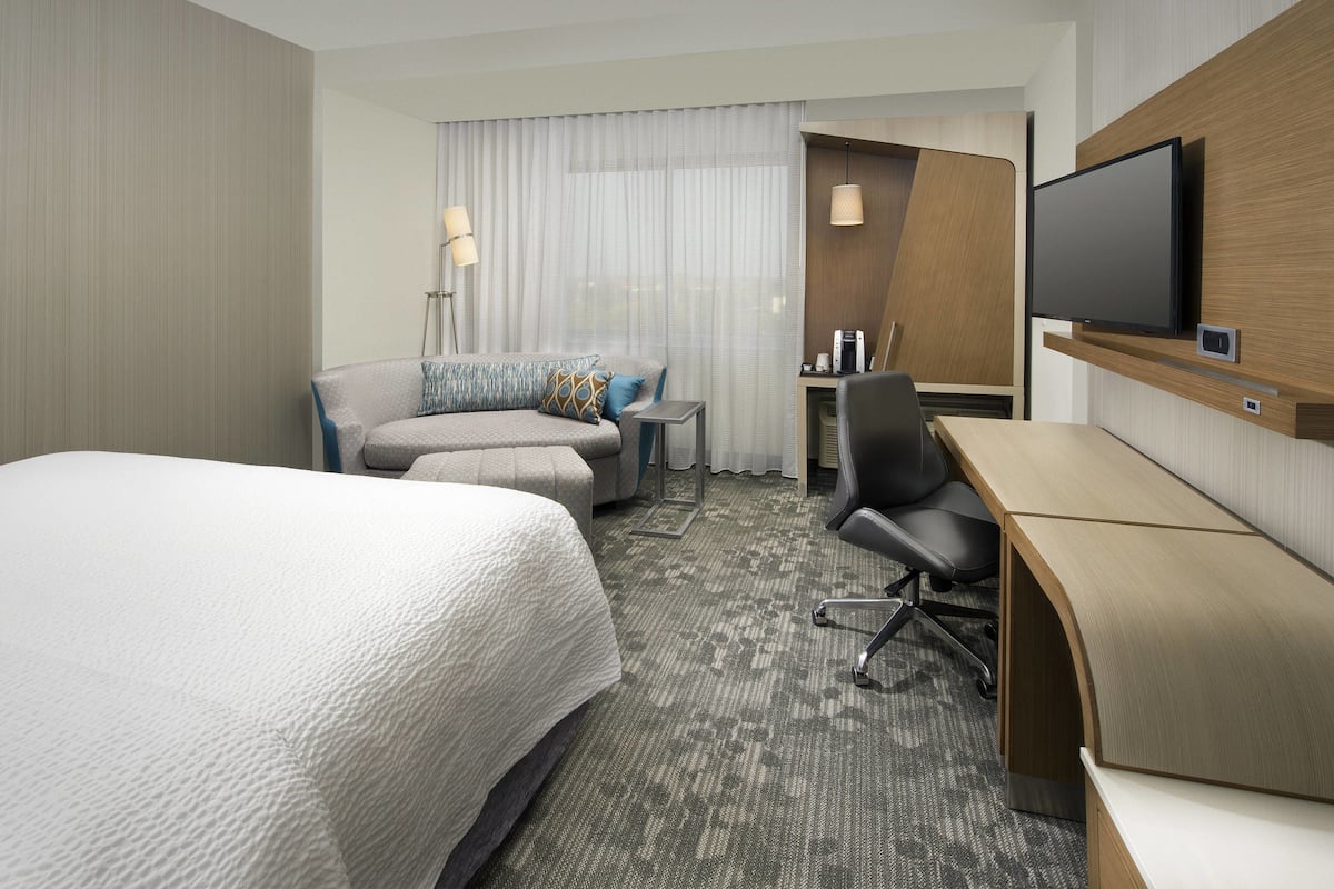 Une chambre d’hôtel avec un grand lit, un canapé, un bureau et une télévision.