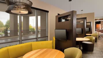 Un interior moderno con una mesa de madera, asientos amarillos y un televisor montado en un panel de madera.