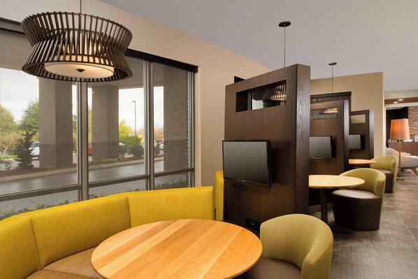 Un interior moderno con una mesa de madera, asientos amarillos y un televisor montado en un panel de madera.