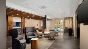 A modern lobby with seating areas, a flat-screen TV, and a large window.