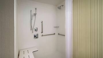 A shower with grab bars, a handheld showerhead, and a shower control panel.